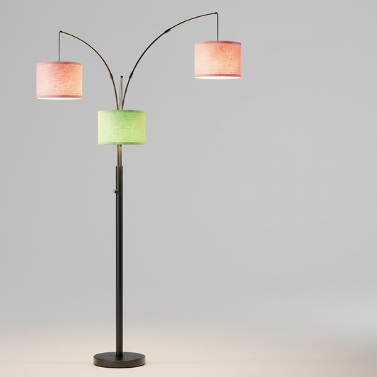 Colorful floor lamp with three lampshades in a room with a sofa and plant.